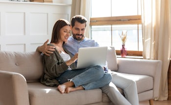 Young Caucasian couple rest at home using laptop